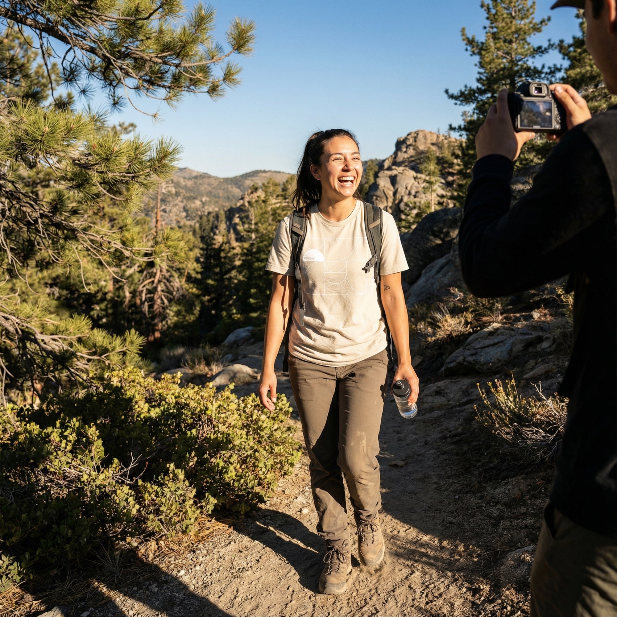 Woman hiking in a forest with another person taking a photo