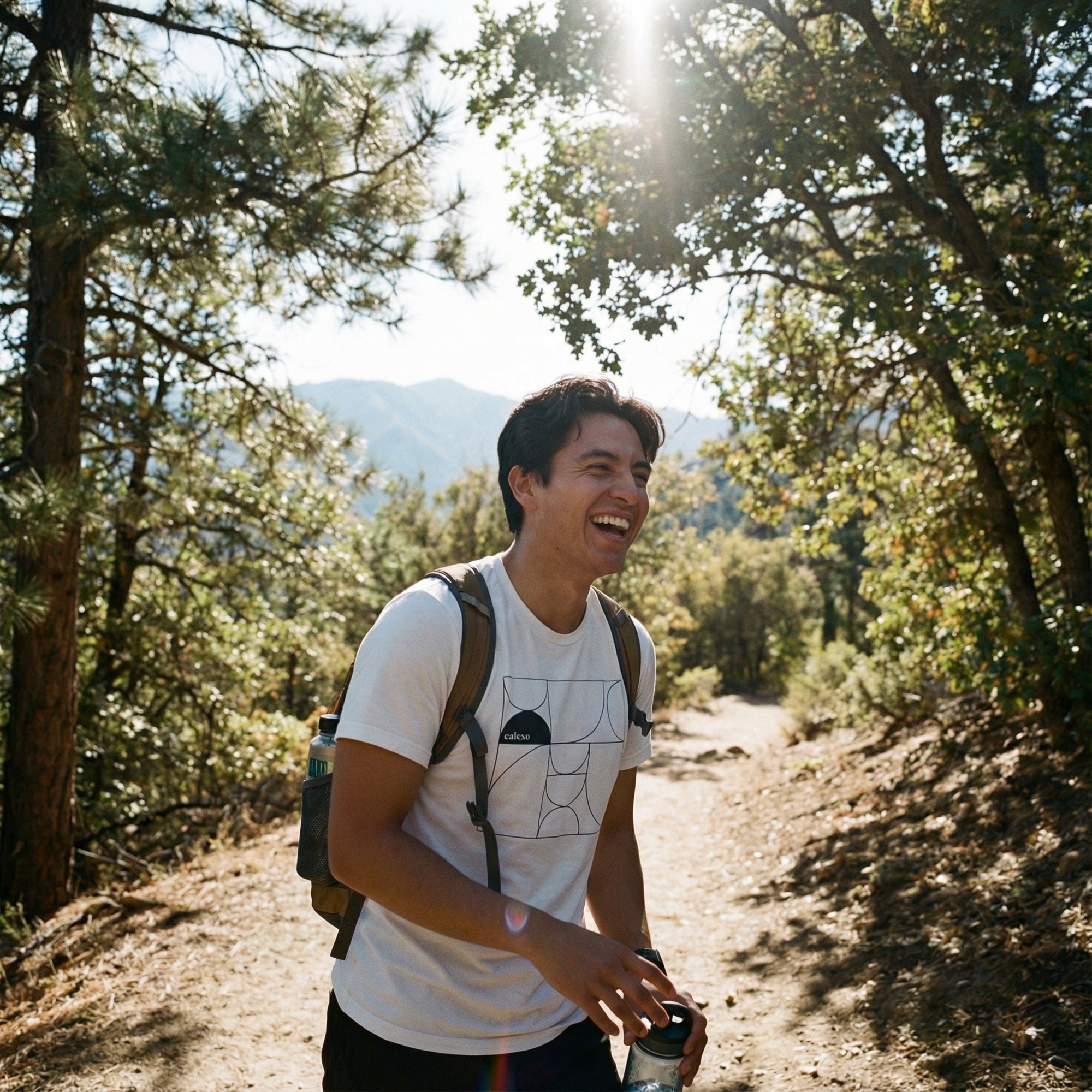 Man hiking on a trail with trees and mountains in the background
